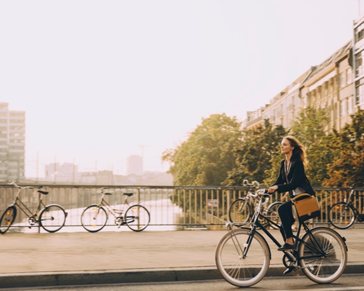 Eine Frau fährt mit dem Fahrrad über eine Brücke.