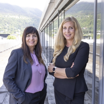 2 Frauen stehen auf einer Terrasse und sehen in die Kamera