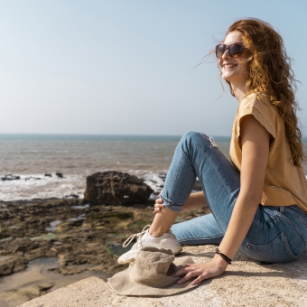 Frau sitzt in der Nähe eines Strandes und sieht in die Ferne