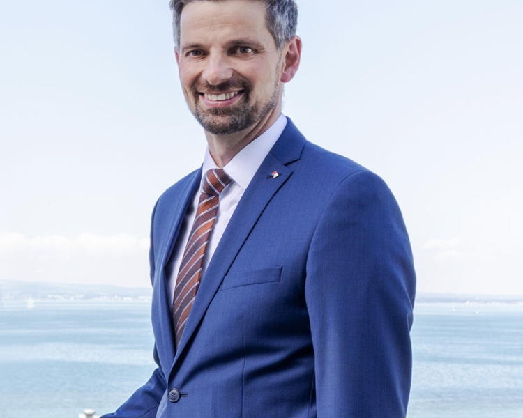 Ein Mann trägt einen blauen Anzug und lächelt in die Kamera
