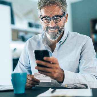 Ein Mann blickt auf sein Smartphone, um sich via Gesichtserkennung anzumelden