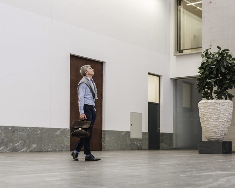 Mann mit Hemd läuft in einer Bankfiliale herum.