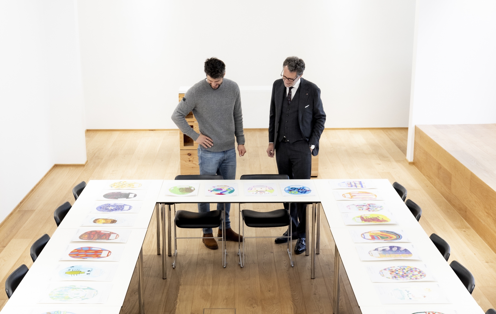 Zwei Männer sehen sich Plakate auf verschiedenen Tischen an.