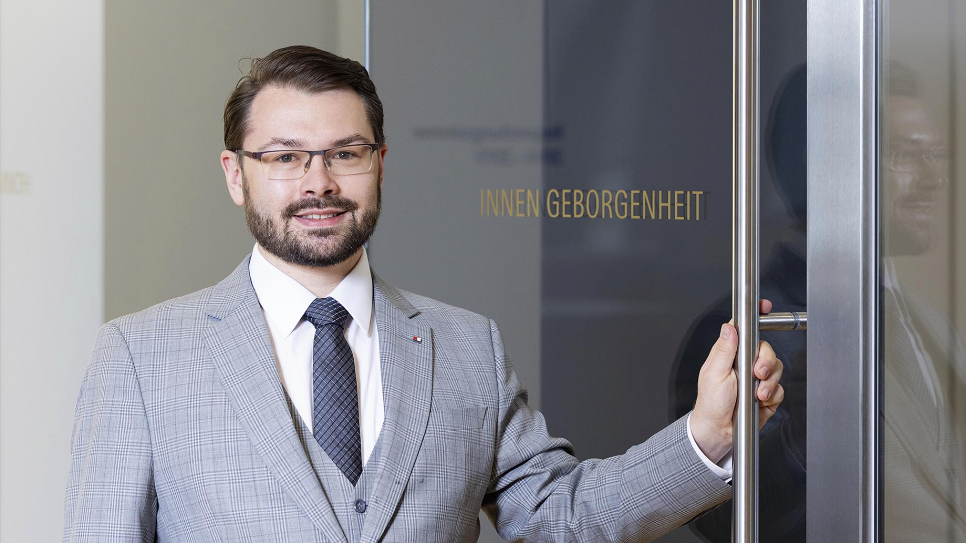 Ein Mann mit einer Brille in einem grauen Anzug