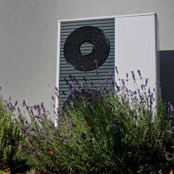 Ein Wärmepumpe mit Pflanzen im Vordergrund