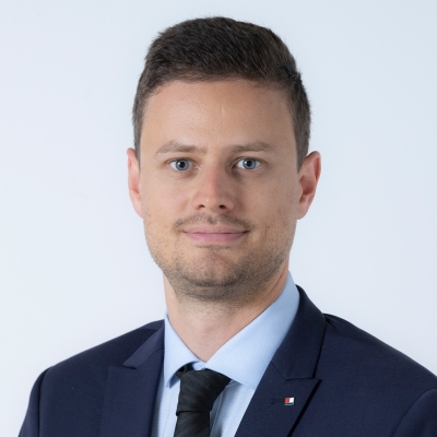 Björn Tretter trägt einen dunkelblauen Anzug, ein hellblaues Hemd und eine schwarzer Krawatte