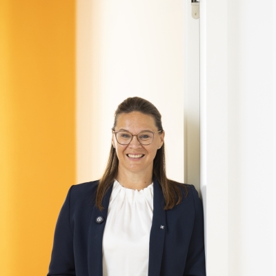 Ein Frau steht in einer Türöffnung und trägt einen blauen Blazer