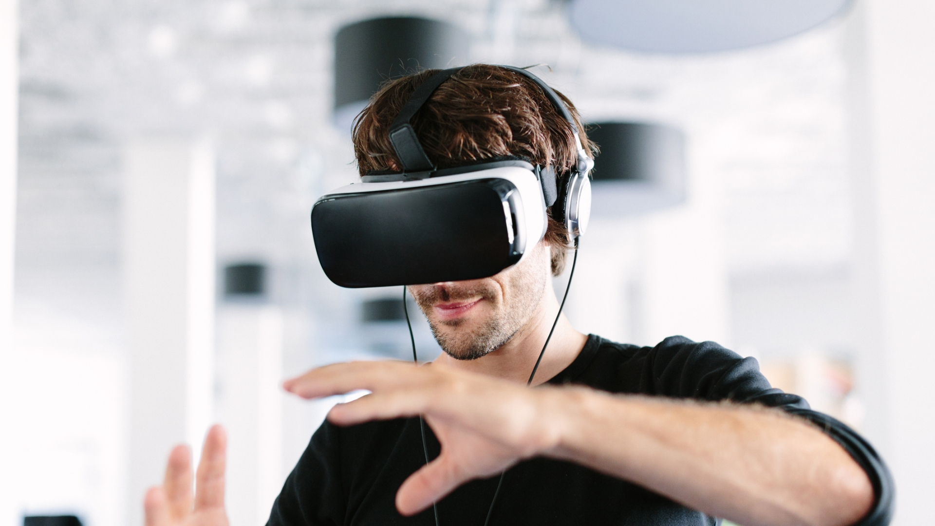 Junger Mann mit VR-Brille, der im Büro gestikuliert.