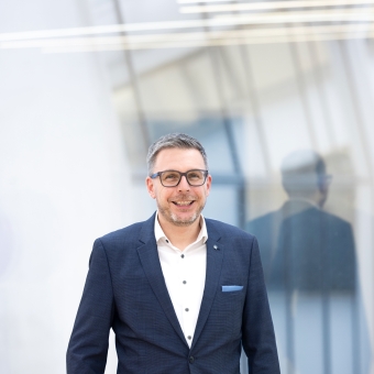 Simon Knittel, Experte für Corporate & International Finance bei der BTV Vier Länder Bank, trägt einen blauen Anzug.