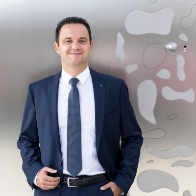 BTV Mitarbeiter Mario Scherl steht in einem blauen Anzug vor der Eingangstüre der BTV Stadtforum in Innsbruck