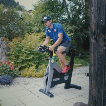 Skirennfahrer Johannes Strolz trainiert auf einem Hometrainer auf einer Terrasse.