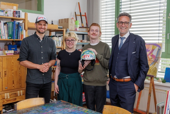 BTV Vorstandsvorsitzender Gerhard Burtscher und Skirennfahrer Johannes Strolz besuchen im Rahmen des BTV Helmwettbewerbs die Lebenshilfe Wien und posieren gemeinsam mit Künstler Sascha und einer Begleitperson vor der Kamera.