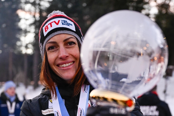 Skeletonpilotin Janine Flock zeigt stolz ihren Pokal für den EM‑Weltcupsieg 2025.