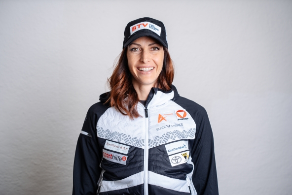 Skeletonpilotin Janine Flock posiert zum Kick‑off des Saisonsstarts 2025 und trägt dabei Sportkleidung ihrer Sponsoren.