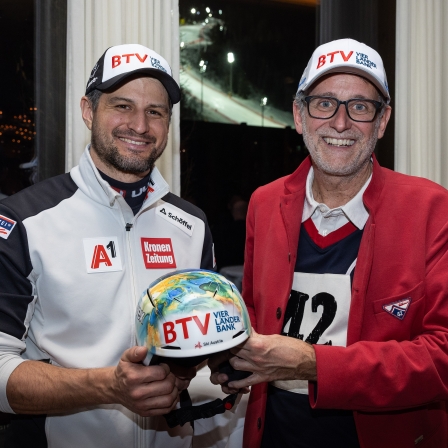 Skirennläufer Johannes Strolz und Vorstandsvorsitzender BTV Vier Länder Bank AG Gerhard Burtscher halten einen Skihelm fest.