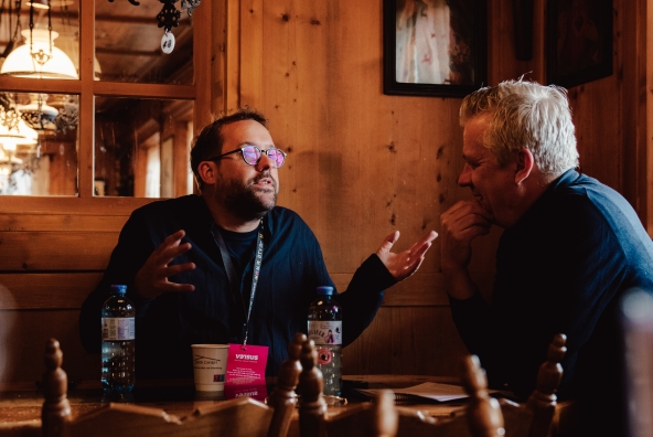 Paul Ronzheimer diskutiert beim versus Festival 2026 engagiert ein Thema mit einem Kollegen an einem Tisch sitzend.
