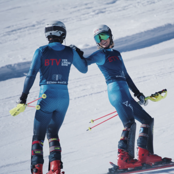Marlies und Benni Raich stehen als BTV Markenbotschafter auf einer Skipiste und geben sich lächelnd die Hand.