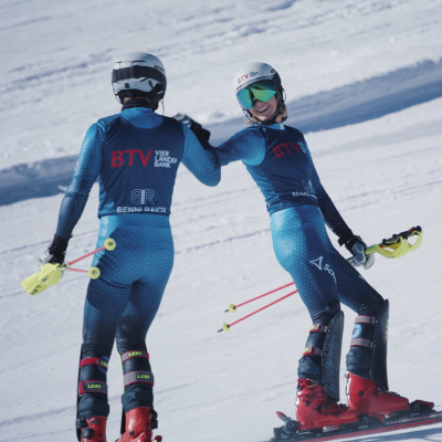 Marlies und Benni Raich stehen als BTV Markenbotschafter auf einer Skipiste und geben sich lächelnd die Hand.