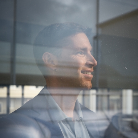 Benjamin Raich steht an einem Fenster uns sieht nach außen.