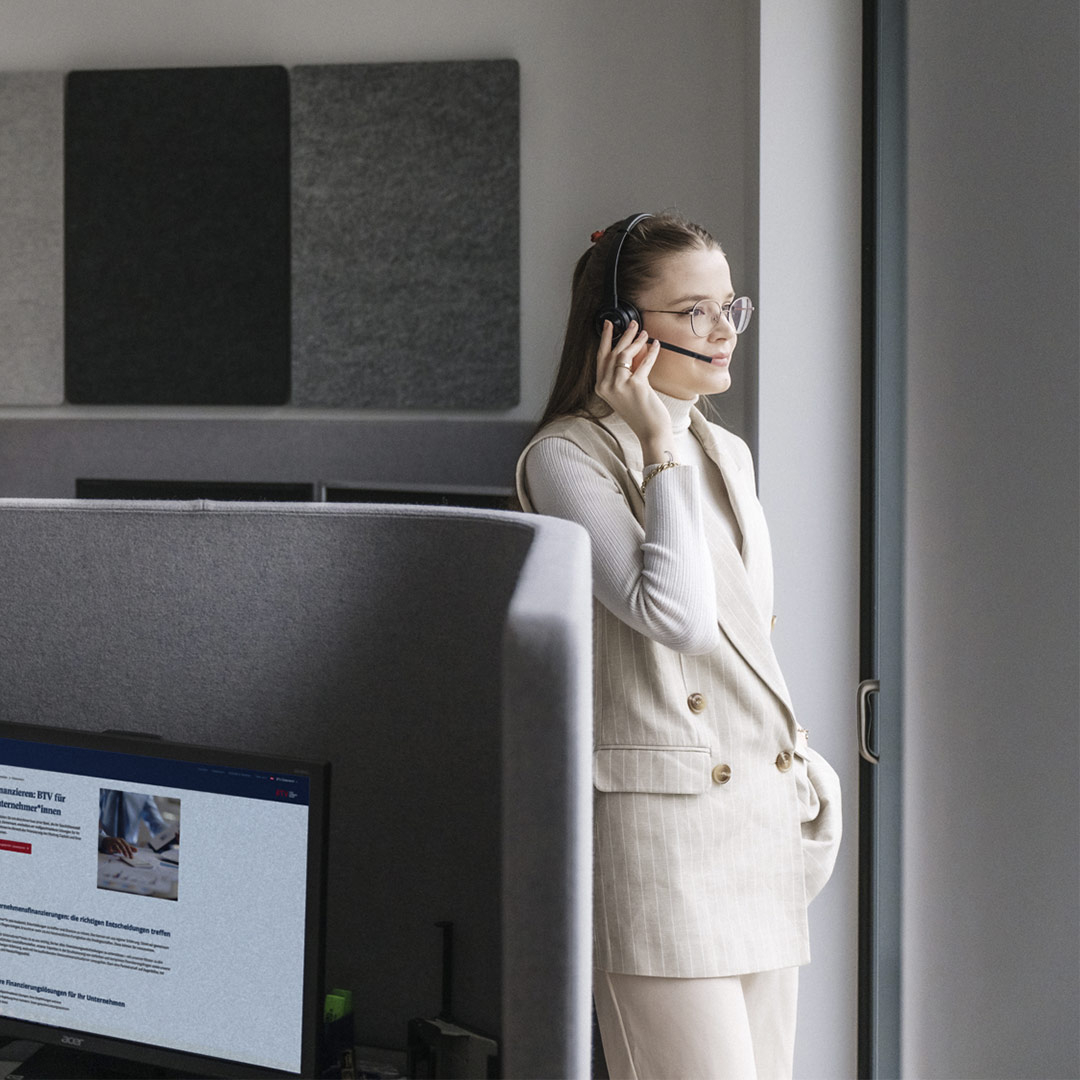 Eine Frau telefoniert mit einem Headset und schaut nach draußen.